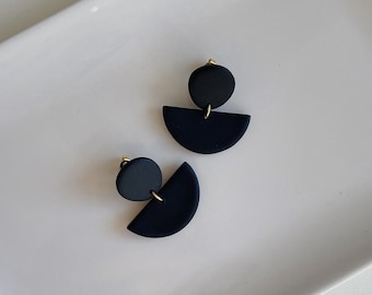 Può includere: Un paio di orecchini geometrici neri con un design a semicerchio e cerchio.
