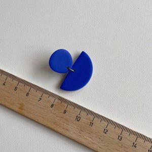 K&ouml;nnte beinhalten: Ein Paar blaue Ohrringe aus Polymer Clay. Ein Ohrring ist ein Halbkreis und der andere ein Kreis. Die Ohrringe haben einen Durchmesser von etwa 2,5 cm.
