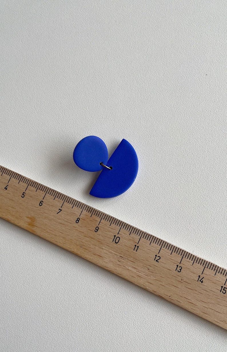 K&ouml;nnte beinhalten: Ein Paar blaue Ohrringe aus Polymer Clay. Ein Ohrring ist ein Halbkreis und der andere ein Kreis. Die Ohrringe haben einen Durchmesser von etwa 2,5 cm.