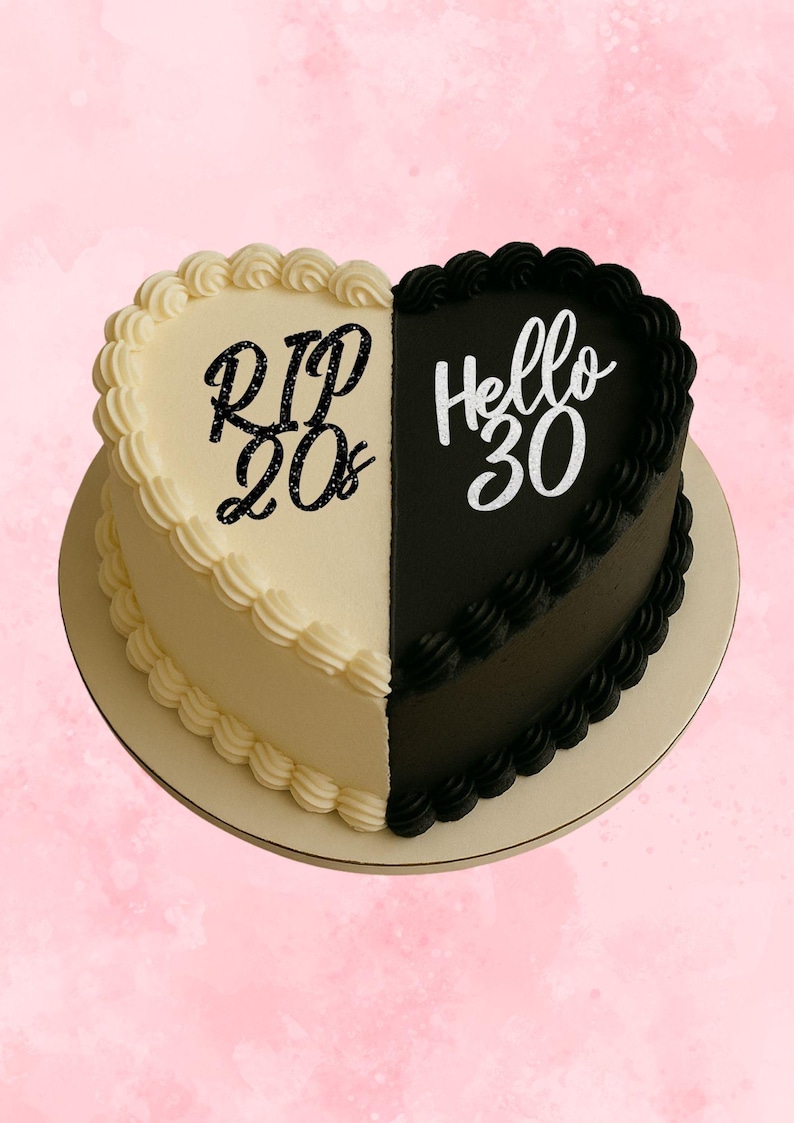 May include: A heart-shaped cake, split in half, with a cream-colored side and a black side. The cream side says "RIP 20s" in black glitter, and the black side says "Hello 30" in white. The cake sits on a round, light-colored cake board.