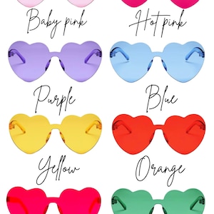 May include: A collection of heart-shaped sunglasses in various colors, including baby pink, hot pink, purple, blue, yellow, orange, red, and green. Each pair has a matching frame and lenses, with the color names written in cursive below.