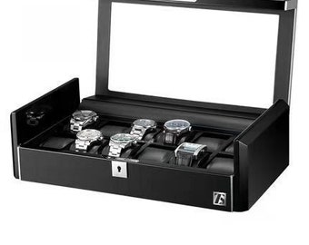 May include: A black watch display case with a clear glass top, showcasing several wristwatches. The case has a lock and a built-in light. The watches are displayed on individual cushions, offering a stylish storage solution for watch collectors.