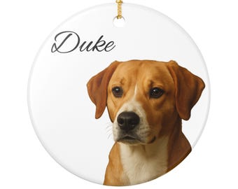 Könnte beinhalten: Runder, weißer Keramikschmuck mit einer goldenen Schnur zum Aufhängen. Der Schmuck zeigt ein Porträt eines braun-weißen Hundes mit dem Namen "Duke" in Schreibschrift. Der Hund hat braune Ohren und eine weiße Brust.