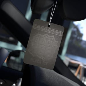 Op de afbeelding: Een zwarte auto luchtverfrisser met de tekst "CAR AIR FRESHENER" bovenaan en "BLACK ICE" in een gestileerd ontwerp. De verfrisser hangt aan een touwtje in een auto.
