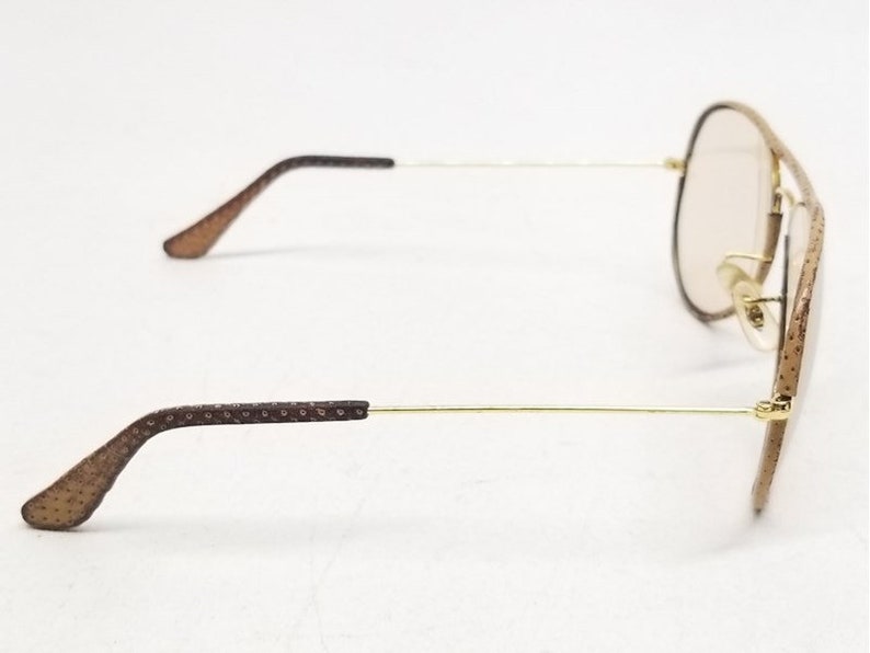 May include: Brown aviator sunglasses with gold metal frames and brown patterned arms.