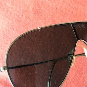 May include: A pair of gold-rimmed aviator sunglasses with brown lenses. The sunglasses have a thin metal frame and are in good condition.