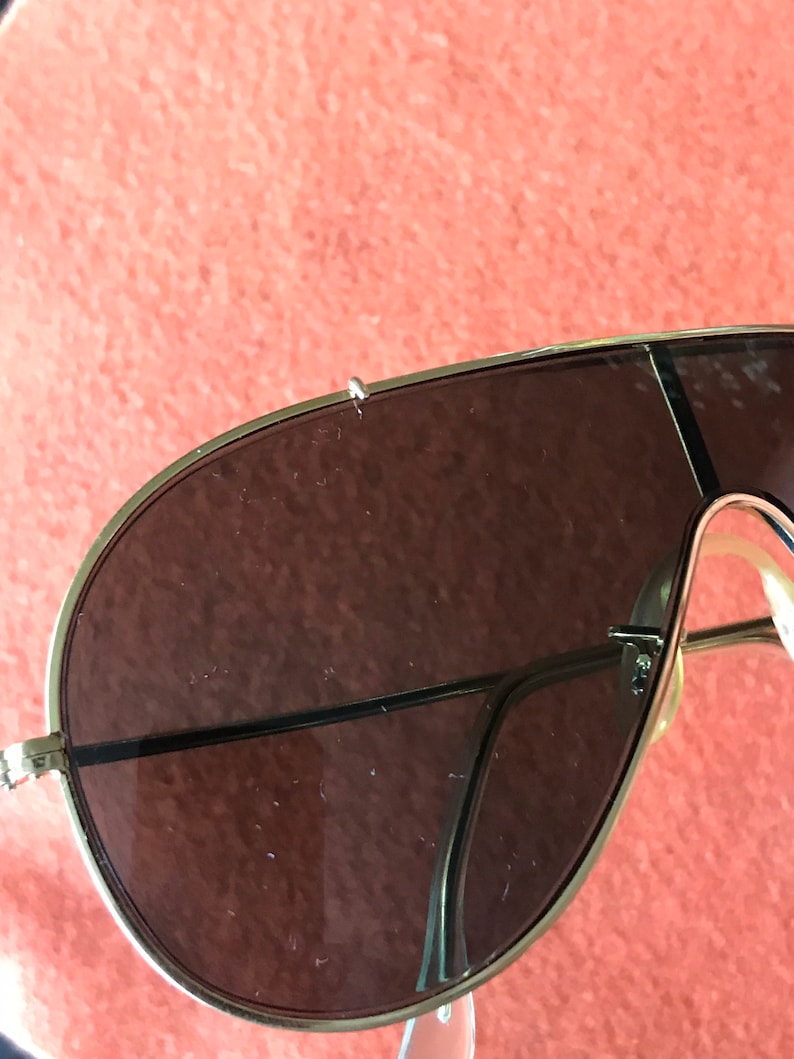 May include: A pair of gold-rimmed aviator sunglasses with brown lenses. The sunglasses have a thin metal frame and are in good condition.