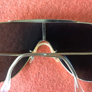 May include: Gold-tone aviator sunglasses with a double bridge and dark lenses. The sunglasses have a classic design and are in good condition.