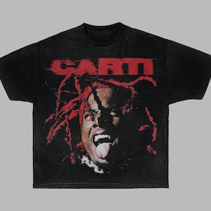 May include: Black t-shirt with a red and white graphic print of a person with red hair and a tongue sticking out. The text 'CARTI' is printed in red above the graphic.