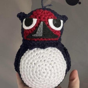 Puede incluir: Juguete de peluche de pingüino de crochet con un esquema de colores rojo, blanco y azul. El pingüino tiene una barriga blanca, una cabeza roja y un cuerpo azul. Los ojos del pingüino son negros con pupilas blancas.