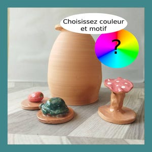 Könnte beinhalten: Eine terrakottafarbene Keramikvase mit kleiner Öffnung, begleitet von drei kleinen Keramikfiguren: einer Erdbeere, einer Schildkröte und einem Pilz. Das Bild enthält den Text "Les Demains dans la Terre" und "Choisissez couleur et motif".