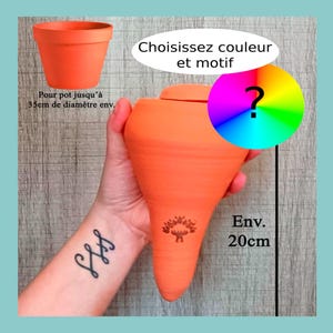 Könnte beinhalten: Ein orangefarbener Keramiktopf und ein passender, länglicher, vasenförmiger Topf mit Deckel. Der Text lautet "Les Demains dans la Terre" und "Wählen Sie Farbe und Muster". Die Vase ist etwa 20 cm hoch.