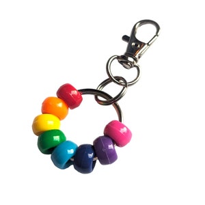 Puede incluir: Llavero con cuentas de colores arcoíris, un anillo de metal plateado y un cierre.