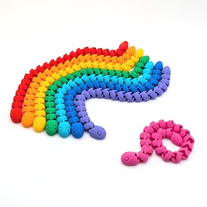 May include: A collection of colorful, articulated snake toys in a rainbow of hues. The toys are made of plastic and have a segmented design, with a rounded head and a curved body. One pink snake toy is also present.