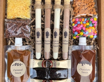 May include: A gift box filled with ingredients to make four different flavored frappés. The box includes four glass test tubes with labels for vanilla, mocha, cookies cream, and toffee frappés. There are also two pouches of sauce, one caramel and one chocolate, as well as sprinkles, chocolate chips, and caramel squares.