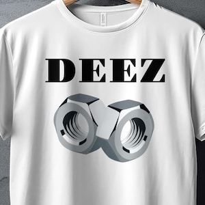 May include: A white short-sleeve t-shirt featuring the black text DEEZ printed above a graphic illustration of two metallic silver hexagonal nuts positioned side by side. The shirt is displayed on a wooden hanger against a textured gray background.