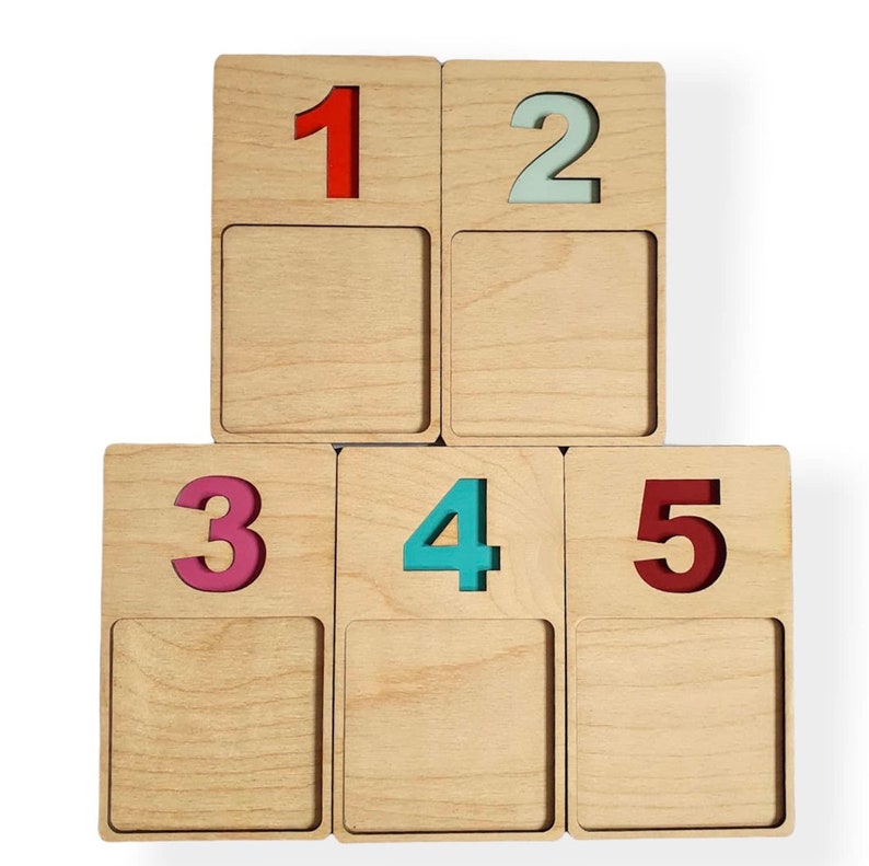 May include: Five wooden blocks stacked in a pyramid shape. Each block has a different number on it, 1 through 5. The numbers are painted in different colours: red, light blue, pink, teal, and maroon.
