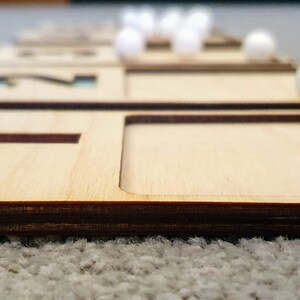 May include: Wooden tray with the number 1 and a slot for a white marble. The tray is part of a set of trays with numbers 1 through 5.
