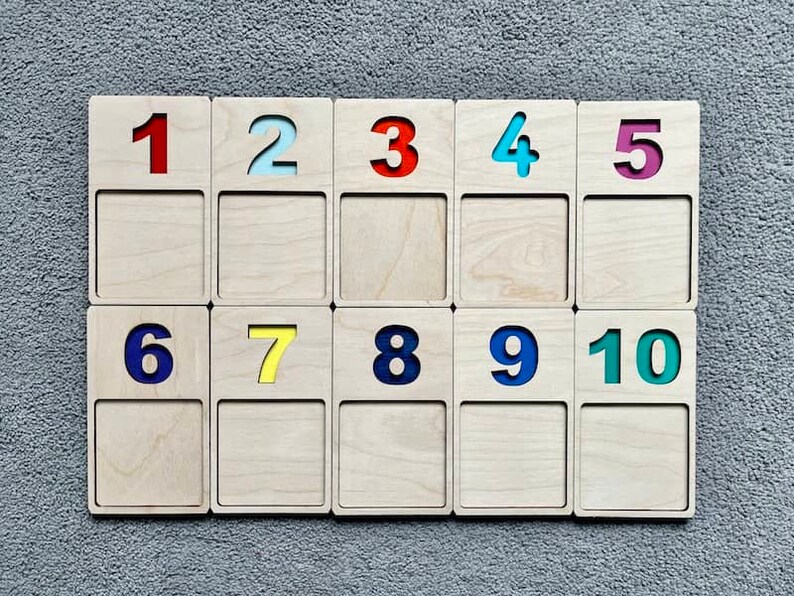 May include: A set of ten wooden tiles with numbers 1 through 10. Each tile has a different coloured number, including red, blue, yellow, green, and light blue.