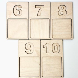 May include: Set of six wooden number tiles with a cutout design. The tiles feature the numbers 6, 7, 8, 9, and 10. Each tile has a blank space below the number.
