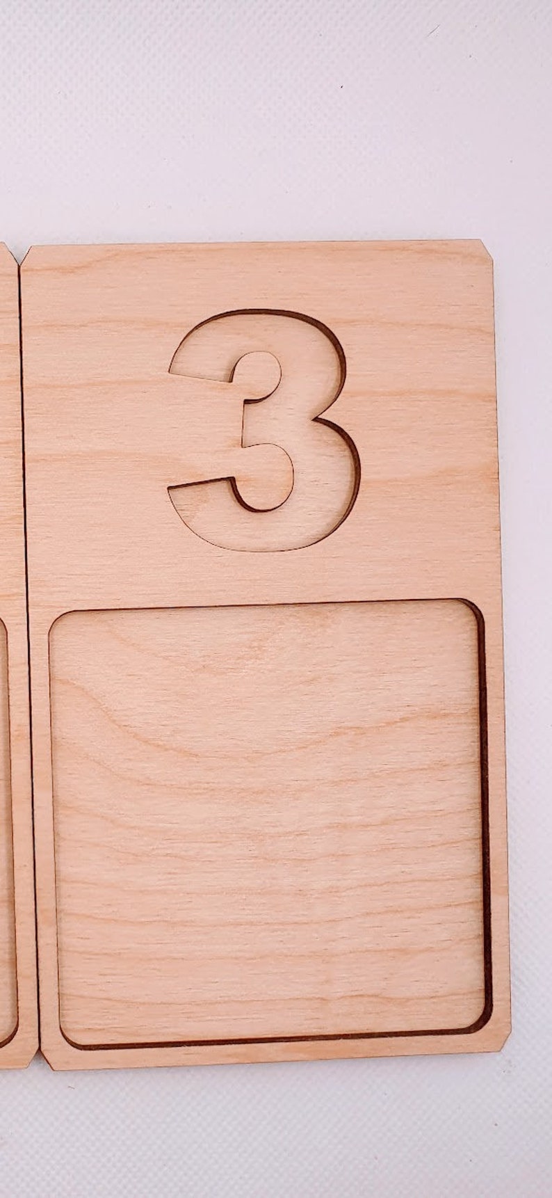 May include: Wooden tray with a cutout of the number 3. The tray has a blank space below the number.