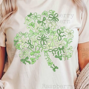 Peut inclure: Un t-shirt blanc avec un motif de tr&egrave;fle vert compos&eacute; de petits n&oelig;uds verts et jaunes. Le motif est centr&eacute; sur le t-shirt. Le texte "Raspberry Pattern Co" et "sublimation design" est en bas de l'image.