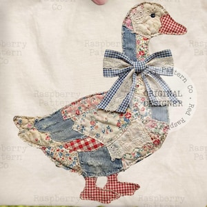 May include: A fabric goose applique with a patchwork design. The goose features a red and white checkered beak and feet, a blue gingham bow, and a variety of floral and denim patches. The words "ORIGINAL DESIGNER" are printed on the fabric.