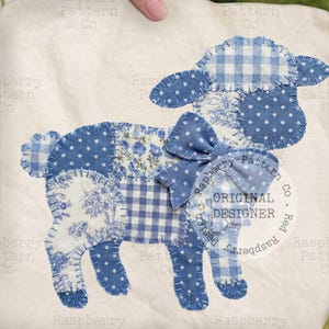 Puede incluir: Un diseño de cordero de patchwork en tonos azules y blancos, con varios patrones como lunares, cuadros y estampados florales. El cordero tiene un lazo y está etiquetado como "ORIGINAL DESIGNER" sobre un fondo blanco.