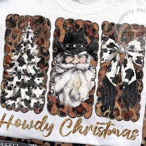 May include: White t-shirt with a festive design featuring a Christmas tree, Santa Claus, and a bow, all with a cowhide pattern. The text "Howdy Christmas" is in gold glitter lettering.