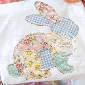 Op de afbeelding: Wit T-shirt met een patchwork konijn ontwerp. Het konijn is gemaakt van verschillende bloemen- en patronenstoffen in pastelkleuren, waaronder roze, blauw en geel. Het ontwerp bevat de tekst "ORIGINAL DESIGNER".