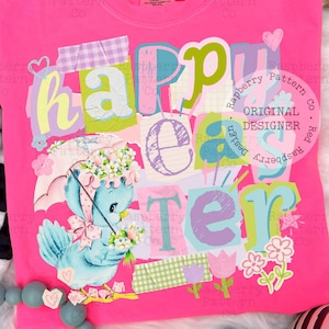 Könnte beinhalten: Ein leuchtend pinkfarbenes T-Shirt mit dem Schriftzug "Happy Easter" in bunten Buchstaben im Patchwork-Stil. Ein blauer Vogel mit Blumenhut und Regenschirm ist darunter abgebildet. Das Shirt hat einen Rundhalsausschnitt und ein "Comfort Colors"-Etikett.