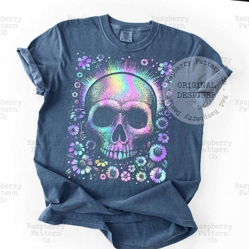 Pu&ograve; includere: T-shirt blu con un design colorato a teschio circondato da fiori. Il teschio ha un effetto iridescente arcobaleno e i fiori sono in tonalit&agrave; viola, blu e giallo. La maglietta ha un girocollo e maniche corte.