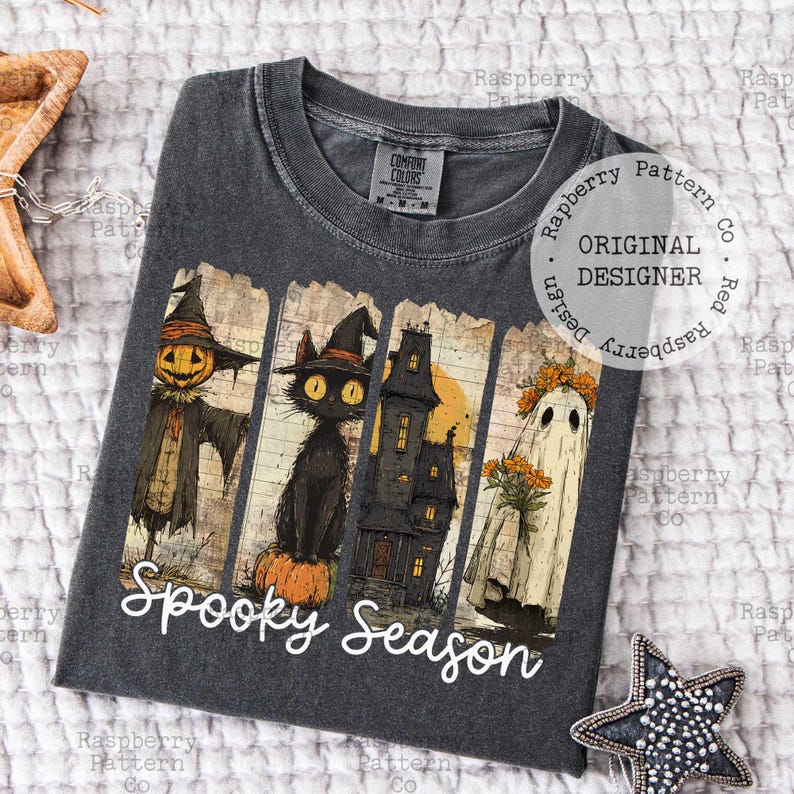 May include: Dark gray t-shirt featuring a Halloween-themed graphic. The design includes a scarecrow, black cat, haunted house, and ghost, with the words "Spooky Season" in white script. The shirt has a crew neck and short sleeves.