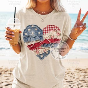 K&ouml;nnte beinhalten: Ein hellbeige T-Shirt mit einem Herzdesign aus Jeansstoff, rot-wei&szlig;em Vichy-Karo, floralem Stoff und Spitze. Das Herz ist mit Sternen und Streifen verziert. Das Shirt ist ein l&auml;ssiger Stil, perfekt f&uuml;r den Alltag.