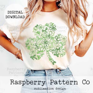 Peut inclure: Un t-shirt blanc avec un design de tr&egrave;fle vert fait de n&oelig;uds. Le tr&egrave;fle est centr&eacute; sur le t-shirt. Le texte "Raspberry Pattern Co. sublimation design" est en bas du t-shirt.