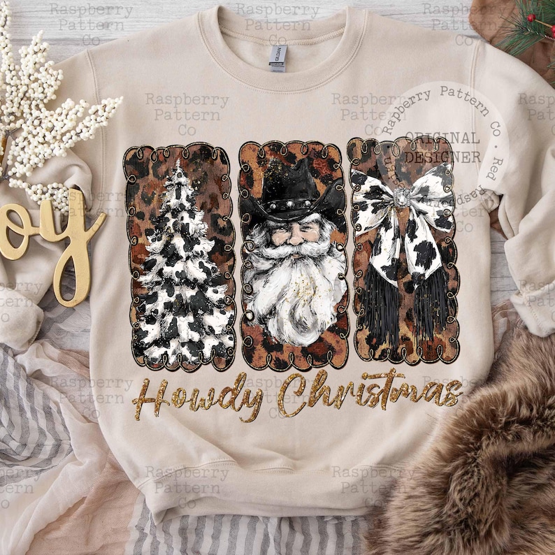 May include: Beige sweatshirt with a festive design. Features three rectangular panels with a Christmas tree, Santa Claus, and a bow, all with a cowhide pattern. The text "Howdy Christmas" is below the panels.