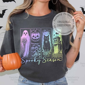 Peut inclure: Un sweat-shirt gris anthracite &agrave; col rond avec une impression graphique de quatre panneaux verticaux montrant un fant&ocirc;me avec un tournesol, une citrouille, un chat noir et une tour en pierre avec des chauves-souris. Le texte Spooky Season est imprim&eacute; en dessous.