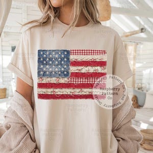 Puede incluir: Camiseta color crema con un dise&ntilde;o de bandera americana en patchwork. La bandera incorpora telas vaqueras, florales y de cuadros en rojo, blanco y azul. La camiseta tiene mangas cortas y un corte holgado.
