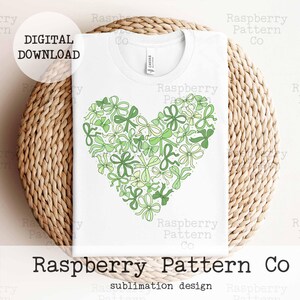 May include: A white t-shirt with a green heart-shaped design made of bows and flowers. The text "Raspberry Pattern Co" is printed below the design. The text "sublimation design" is printed below the company name.