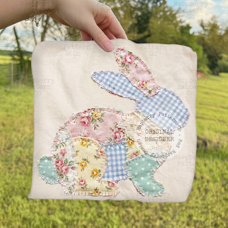 May include: A cream-colored fabric square featuring a patchwork bunny design. The bunny is composed of various floral and gingham fabrics in pastel colors, including pink, blue, and yellow. The text "ORIGINAL DESIGNER" is visible.