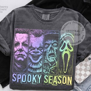 Peut inclure: Sweat-shirt gris fonc&eacute; avec un graphisme de quatre personnages de films d'horreur aux couleurs d&eacute;grad&eacute;es. Le texte "SPOOKY SEASON" est en dessous des images, en lettres majuscules.