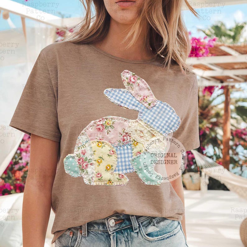 May include: A tan t-shirt featuring a patchwork bunny design. The bunny is made of various floral and gingham fabrics in pastel colors. The shirt has a round neckline and short sleeves. The text "ORIGINAL DESIGNER" is visible.