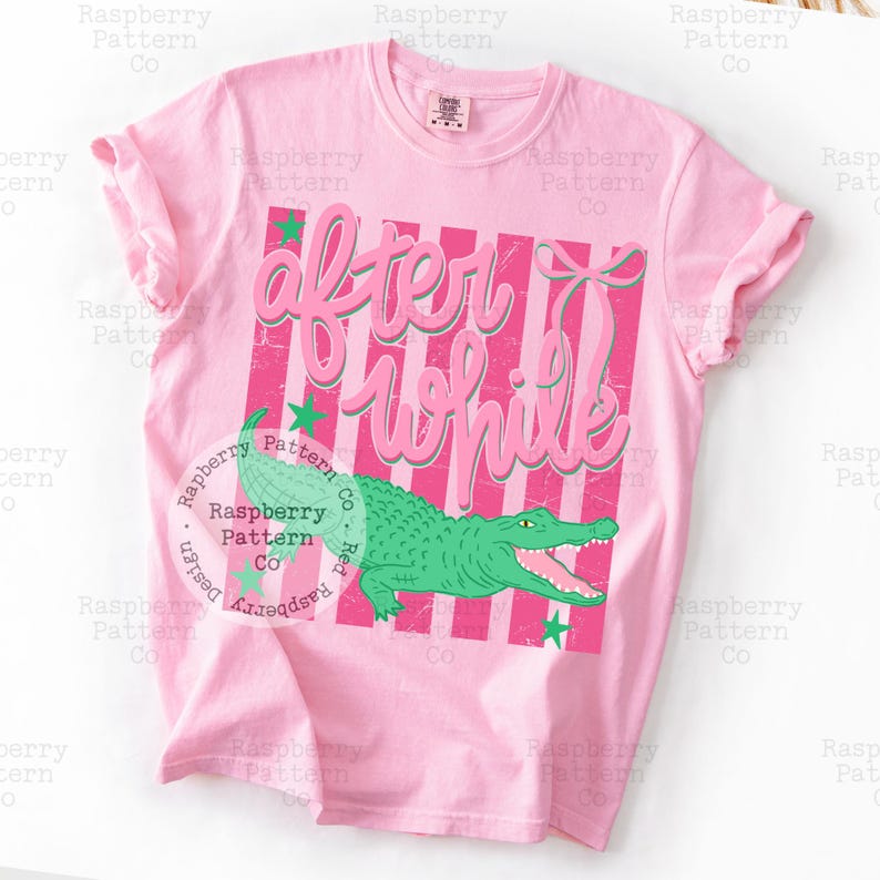 May include: Pink t-shirt with the text "After While" in a pink script font over a pink and white striped background. A green alligator graphic is below the text, with green star accents.