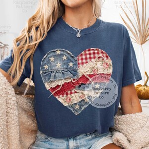 K&ouml;nnte beinhalten: Marineblaues T-Shirt mit einem Patchwork-Herz-Design. Das Herz besteht aus Jeansstoff, rot-wei&szlig;em Vichy, floralen und gepunkteten Stoffen mit Spitzendetails. Das Design enth&auml;lt Sterne und patriotische Farben.
