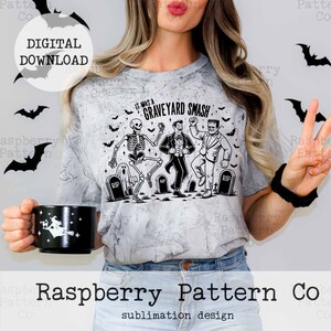 Puede incluir: Un dise&ntilde;o de sublimaci&oacute;n con un esqueleto, un vampiro y un monstruo de Frankenstein bailando con el texto "It was a Graveyard Smash!" impreso en una camiseta gris.