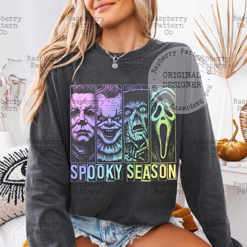 Peut inclure: Sweat-shirt gris fonc&eacute; avec un motif color&eacute; de personnages de films d'horreur, dont Michael Myers et Pennywise. Le texte "SPOOKY SEASON" est affich&eacute; dans une police d&eacute;grad&eacute;e. Un haut &agrave; manches longues pour la saison d'Halloween.