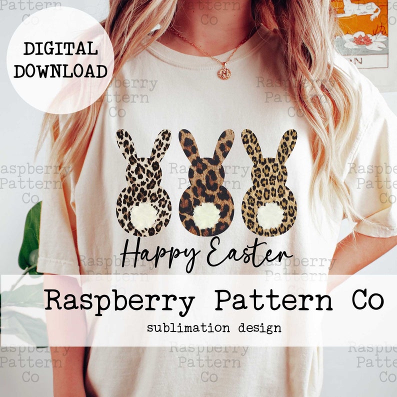 May include: A white t-shirt with a sublimation design featuring three leopard print bunnies with white tails. The bunnies are arranged in a row and the text "Happy Easter" is printed below them. The text "Raspberry Pattern Co. sublimation design" is printed below the bunnies.