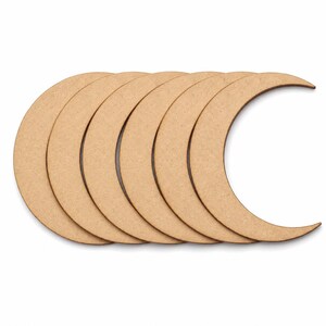 May include: A collection of six crescent moon-shaped wooden cutouts. The cutouts are a light brown color and arranged in a row, with the curved sides facing the same direction. The background is plain white.