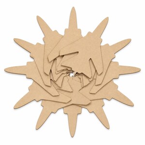 May include: A radial arrangement of tan-colored, die-cut cardboard pieces. The pieces are layered and arranged to resemble a starburst or sun shape. The design is symmetrical and appears to be a craft or decorative element.