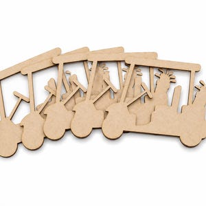 May include: Several unfinished wooden golf cart cutouts are arranged on a white surface. Each cart features a roof, steering wheel, seats, and golf clubs. The cutouts are made of light brown wood.